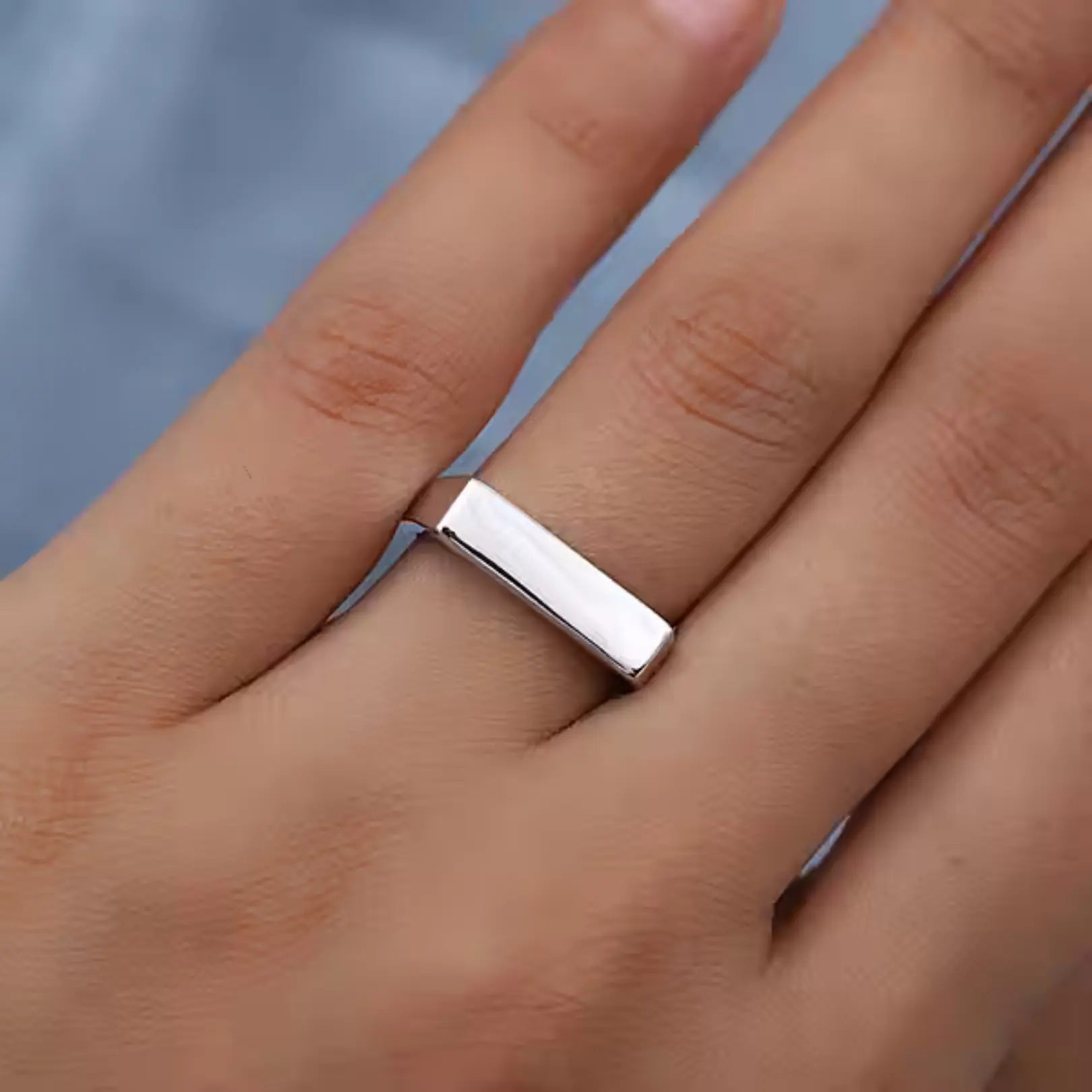  Minimalist silver signet ring shown on a hand, highlighting its sharp lines and stylish fit