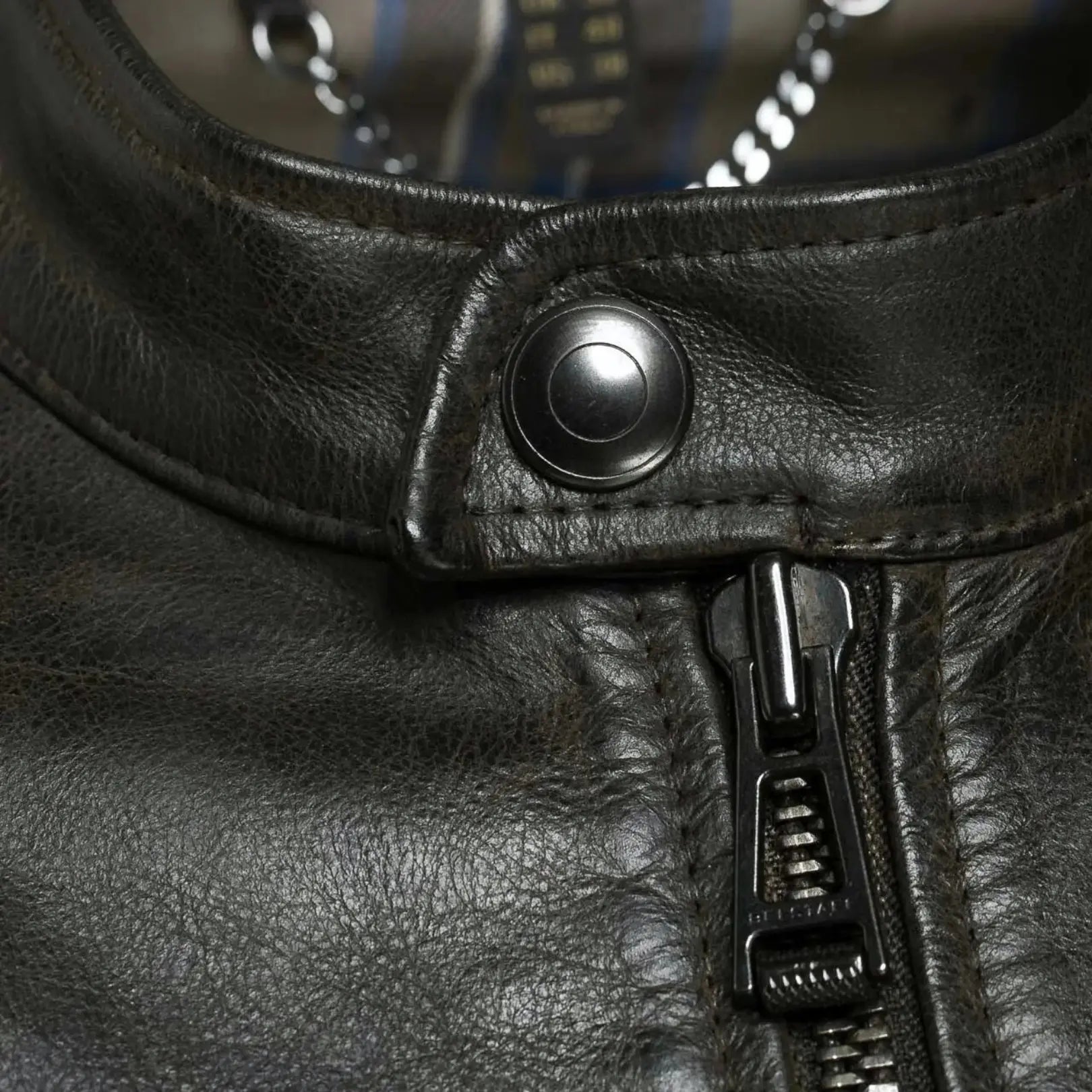 Close-up view of the zipper and stitching detail on a men's black leather jacket, highlighting premium craftsmanship and durable design.
