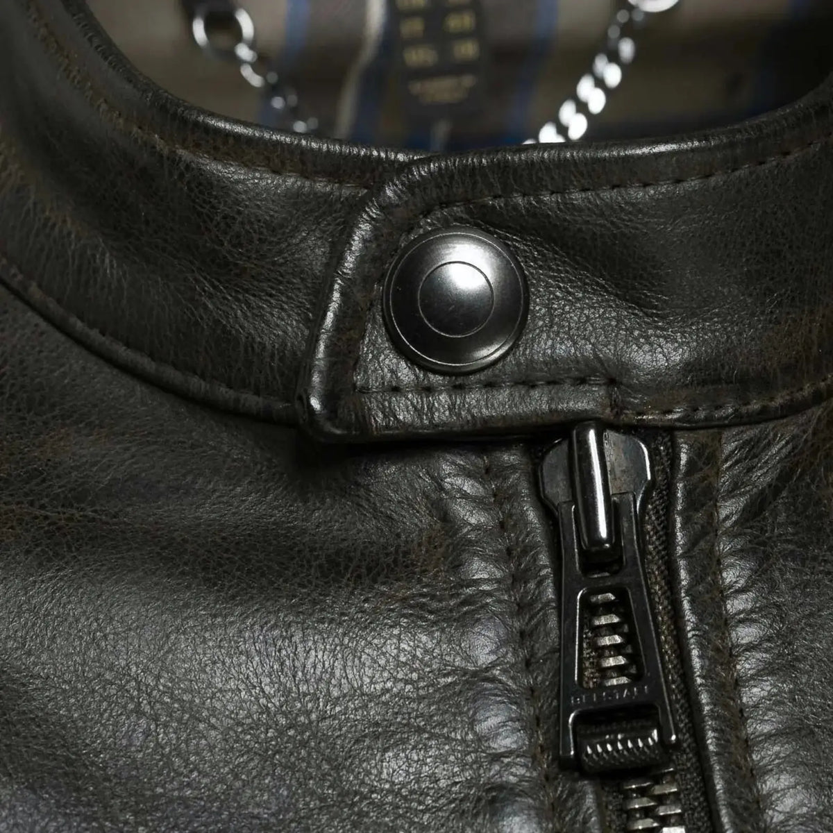 Close-up view of the zipper and stitching detail on a men's black leather jacket, highlighting premium craftsmanship and durable design.
