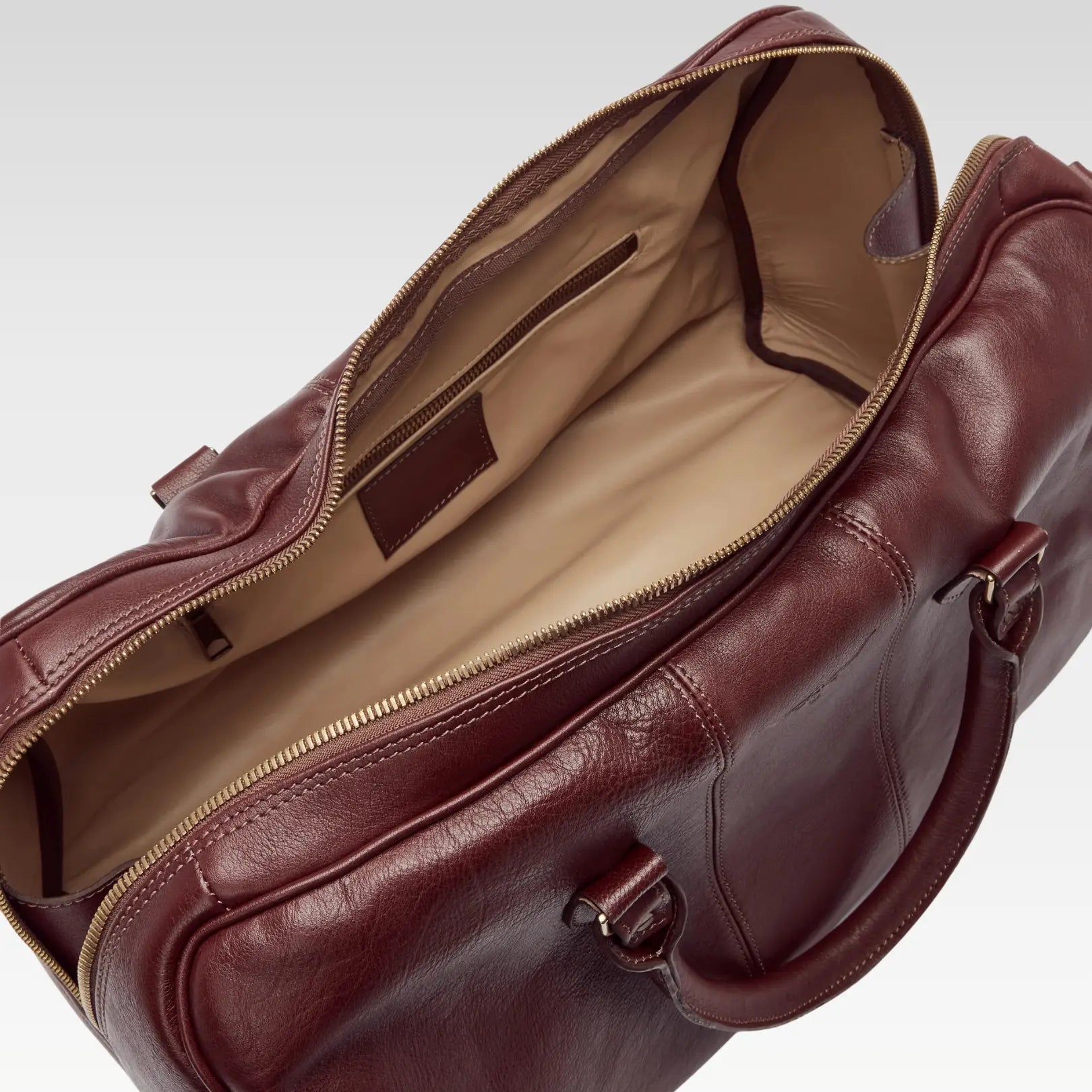 Open view of the Saddler duffle bag interior, highlighting the roomy compartment, smooth floor-to-floor zipper, and organized layout.