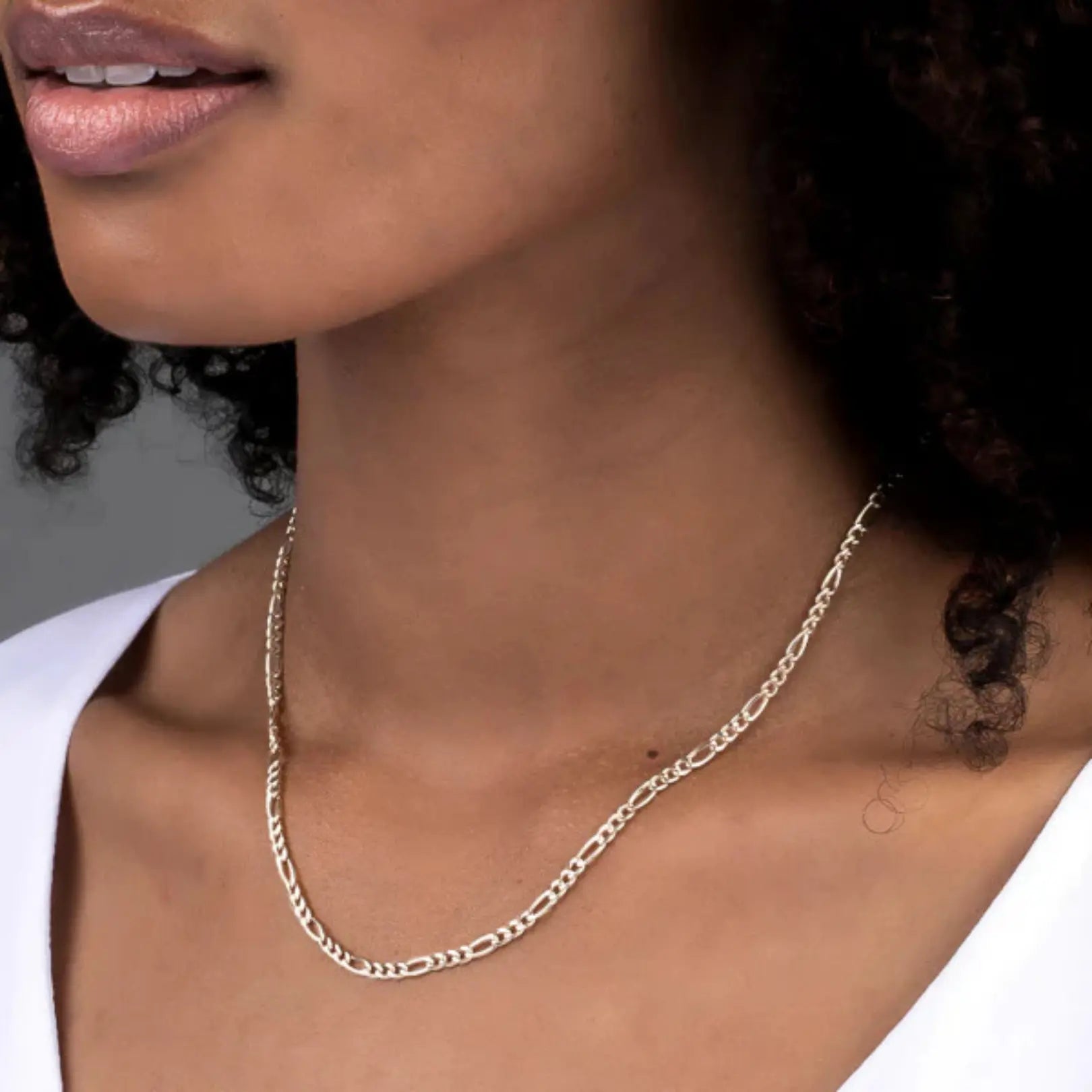 Sterling silver Figaro chain necklace worn by a woman, showcasing the elegant and polished design.