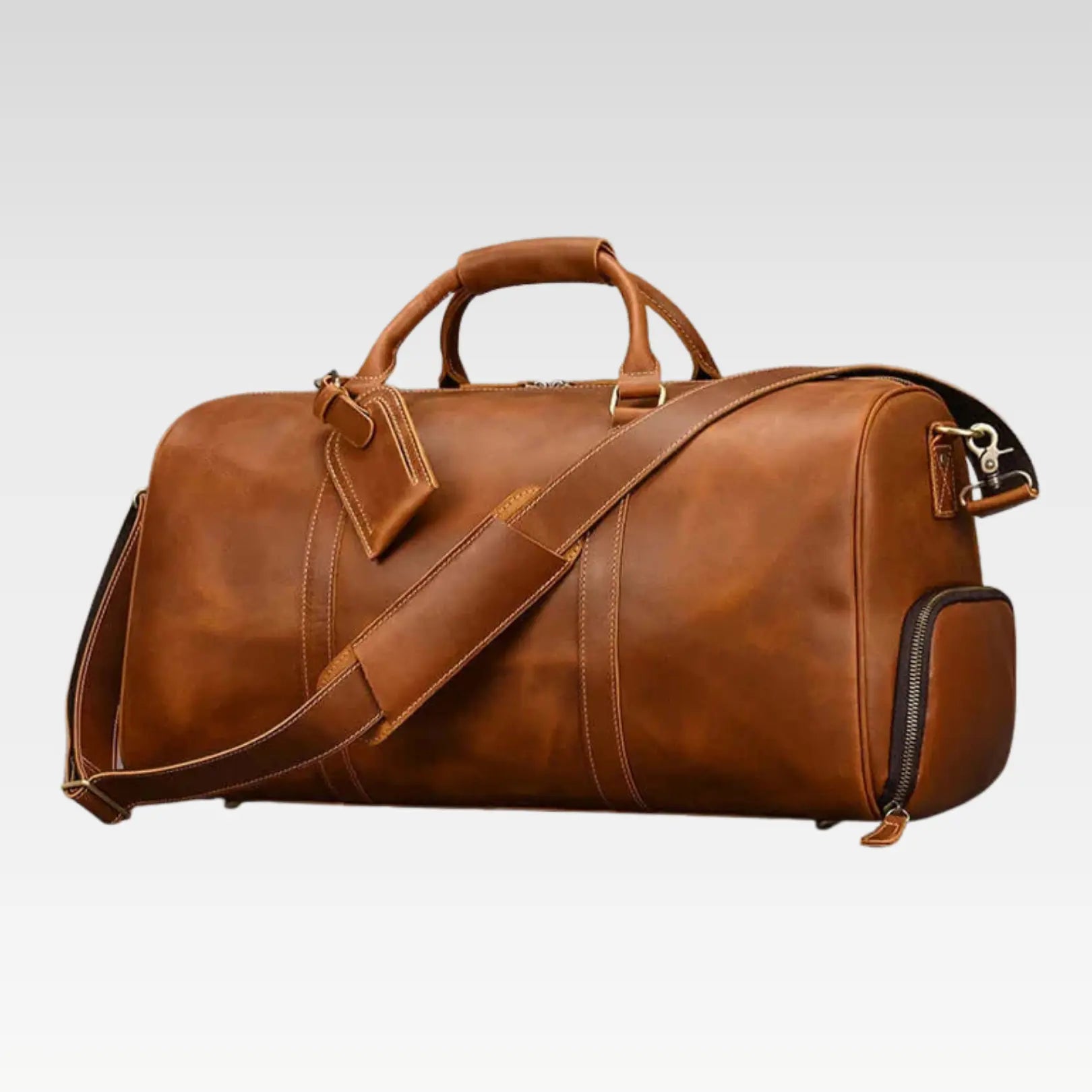 Genuine leather duffle bag displayed on top of a suitcase, showing the front view of The Voyager travel weekender bag.