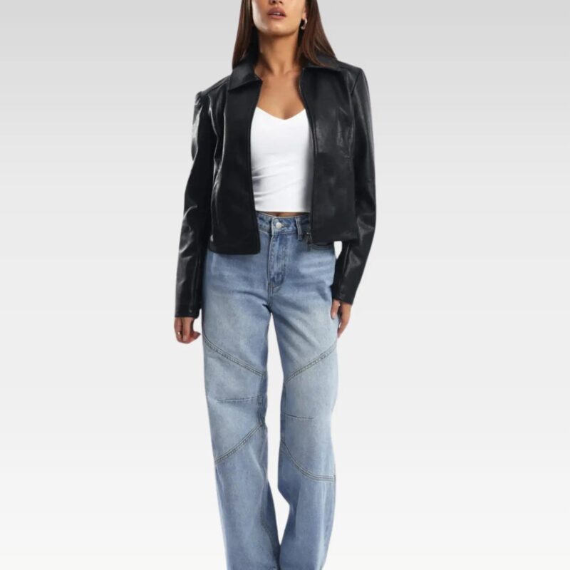 Stylish black leather jacket worn by a woman with raised arms, paired with light blue jeans and a white top, emphasizing its comfortable fit and edgy zippered sleeves for winter fashion.
