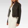Woman wearing black collared leather jacket over white top, showcasing the cropped fit and structured collar design