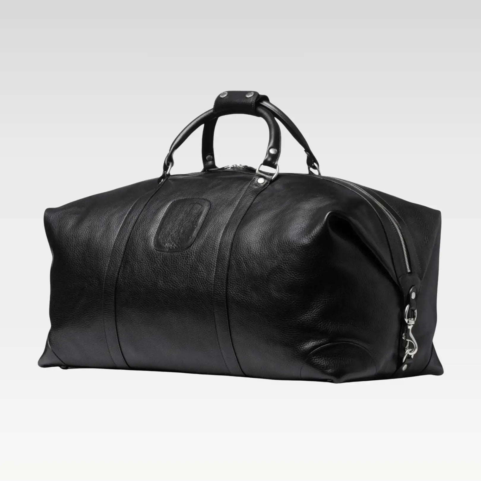 Side-angle view of the Rogue premium Black full-grain leather duffel bag highlighting its brass hardware and classic finish.