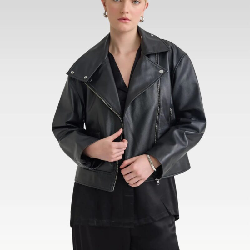 Woman wearing the Sasha biker black leather jacket in  styled with a beige dress and handbag, showcasing the cropped boxy fit and edgy biker details.