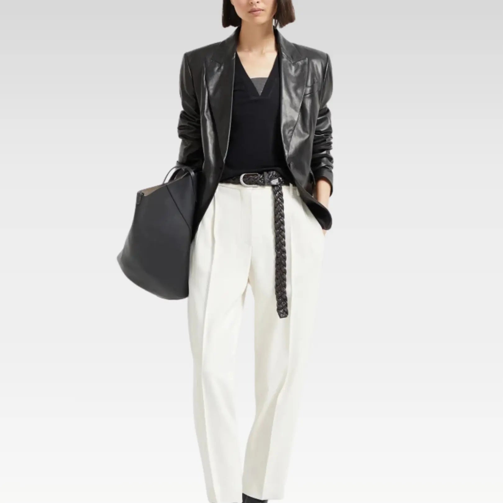 Side profile of a chic women's black leather blazer with a tailored cut, highlighting its vibrant even-toned hue and flattering fit, ideal for office or nightlife styling.