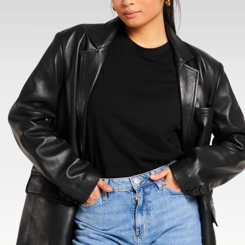 Front view of woman styling oversized sheep leather blazer over black top and blue jeans, combining modern versatility with retro 80s aesthetics.