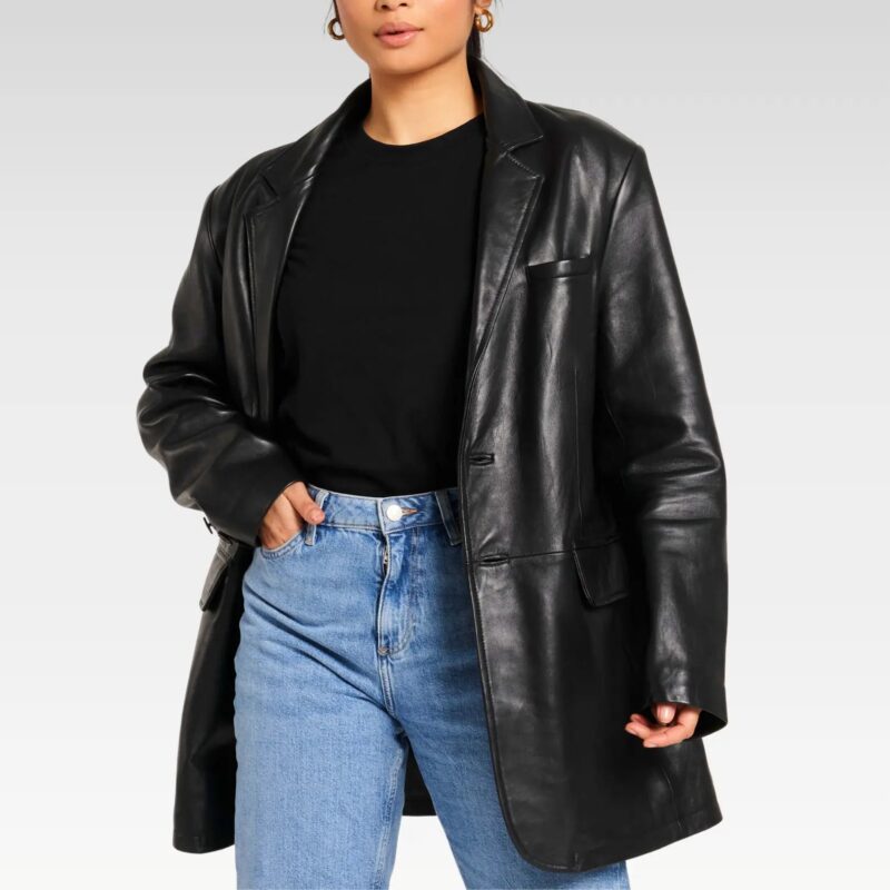 Woman posing with hands in pockets wearing oversized black leather blazer, highlighting the retro 80s design and relaxed fit paired with denim.